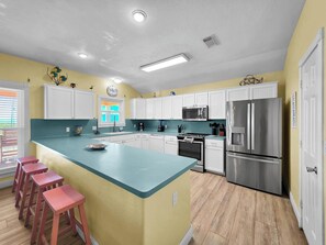 A kitchen with white cabinets, a stainless steel refrigerator, a microwave, and a sink. - Pelican and Palms 3 bed 2.5 baths Sleeps 14 Ocean View 3 minute walk to beach (Crystal Beach)