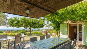 An outdoor dining area with a table and chairs, a pergola, and a view of the landscape.