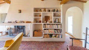 A room with a fireplace, bookshelves, and a yellow chair.