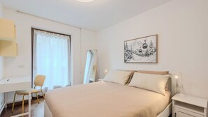 Una camera da letto con un letto, una scrivania, una sedia, un comodino, uno specchio e un quadro appeso al muro.