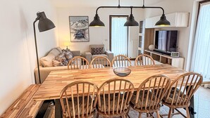Un'area pranzo con un tavolo e sedie in legno, un divano, una lampada e un quadro appeso al muro.