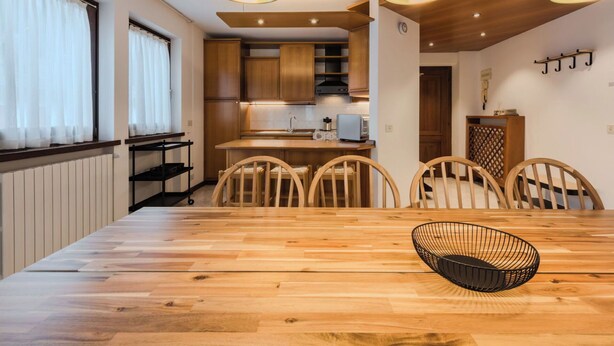 Una cucina moderna con mobili in legno, un tavolo da pranzo con sedie e lampade a sospensione.