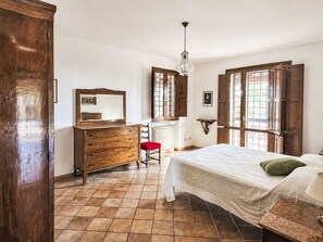 Een slaapkamer met een bed, een kaptafel, een stoel en een raam met uitzicht.