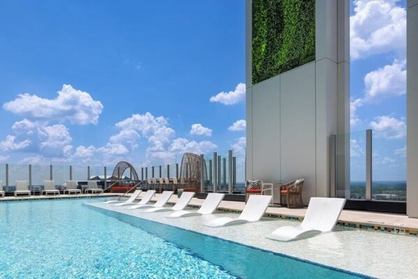 A rooftop pool with lounge chairs, a glass balustrade, and a view of the city skyline. - Club Wyndham Margaritaville- Studio Deluxe (Atlanta)