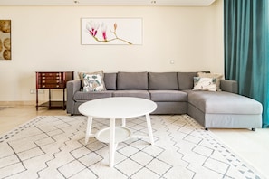 A modern living room with a grey sectional sofa, a white round coffee table, and patterned rugs. - BVQ - Stunning Sea & Golf View Terrace (Benahavis)