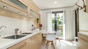 Una cucina moderna con un lavello doppio, mobili in legno e un'area pranzo con sedie bianche e un tavolo.