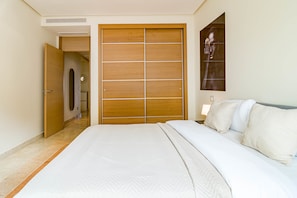 A bedroom with a large bed, a wooden wardrobe, and a wall-mounted artwork. - BVQ - Stunning Sea & Golf View Terrace (Benahavis)