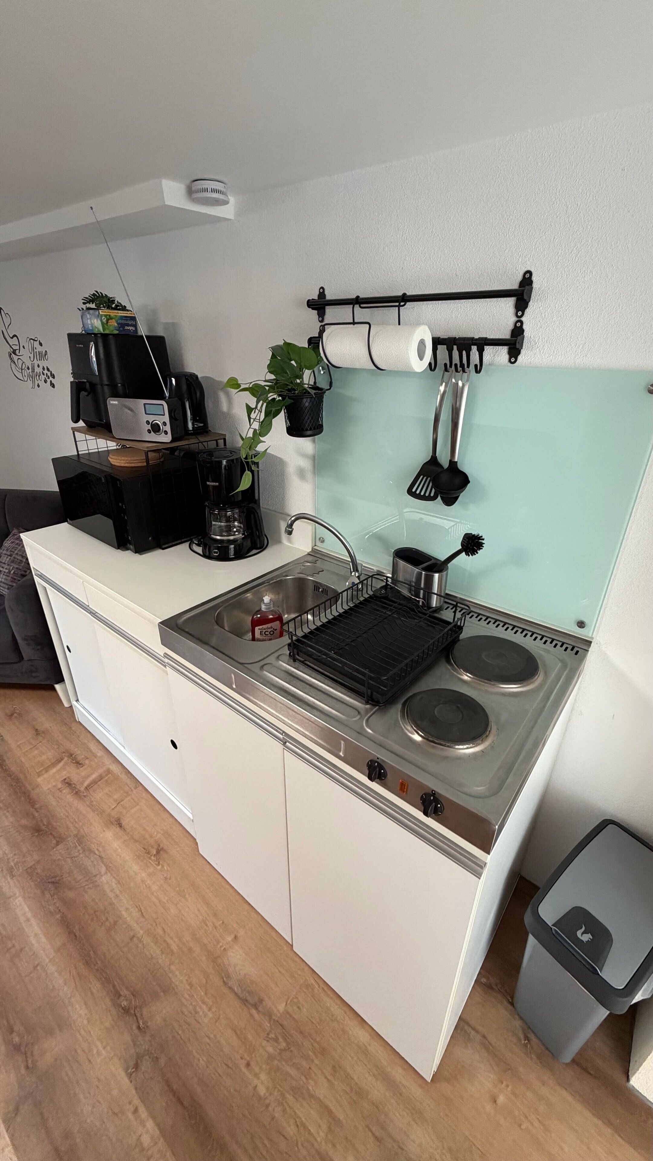 Eine kleine Küchenzeile mit Spüle, Herd und Kaffeemaschine.
