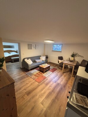 A living room with a sofa, coffee table, and a dining area with a table and chairs. - Cozy 45 m² Apartment in the Vineyards (Bad Kreuznach)