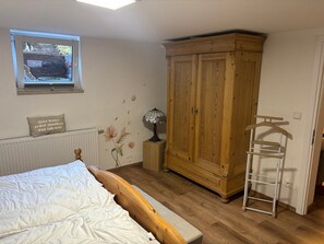 Ein Schlafzimmer mit einem Bett, einem Holzschrank, einer Heizung, einem Fenster mit Blick und einem Nachttisch mit Lampe.