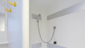 A shower with a handheld showerhead and a wall-mounted faucet.