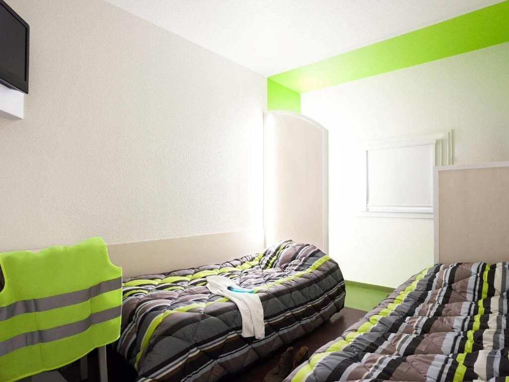 Un dormitorio con dos camas, una silla y un televisor.