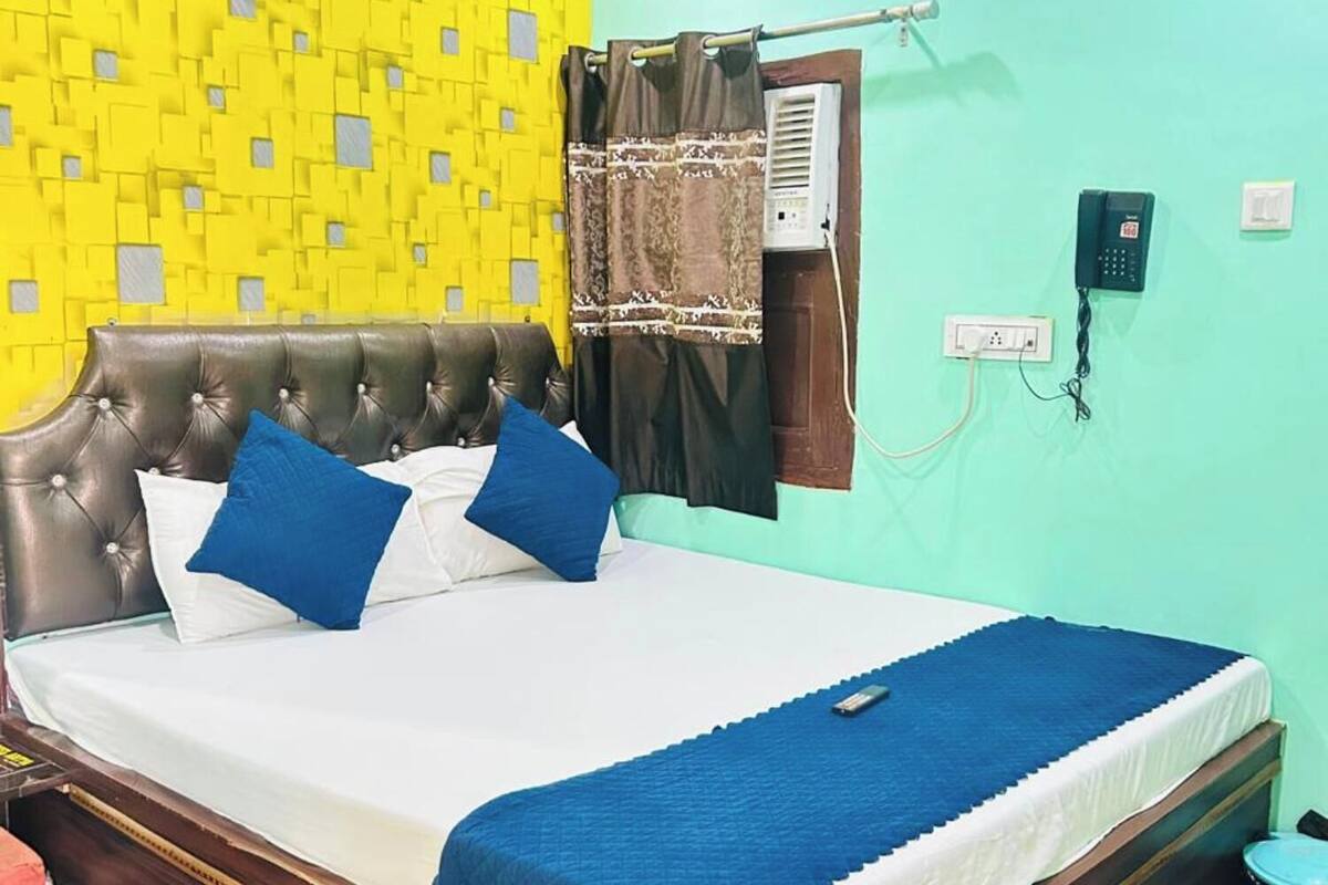 Un dormitorio con cama, ventilador de techo, equipo de aire acondicionado, teléfono y una lámpara de pared.