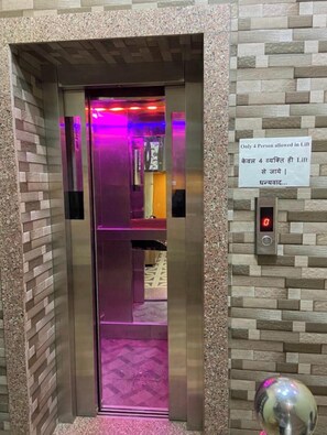 An elevator with a sign indicating a 4-person limit. - Varanasi Hotel Aditya by Ramapura Luxa (Varanasi)