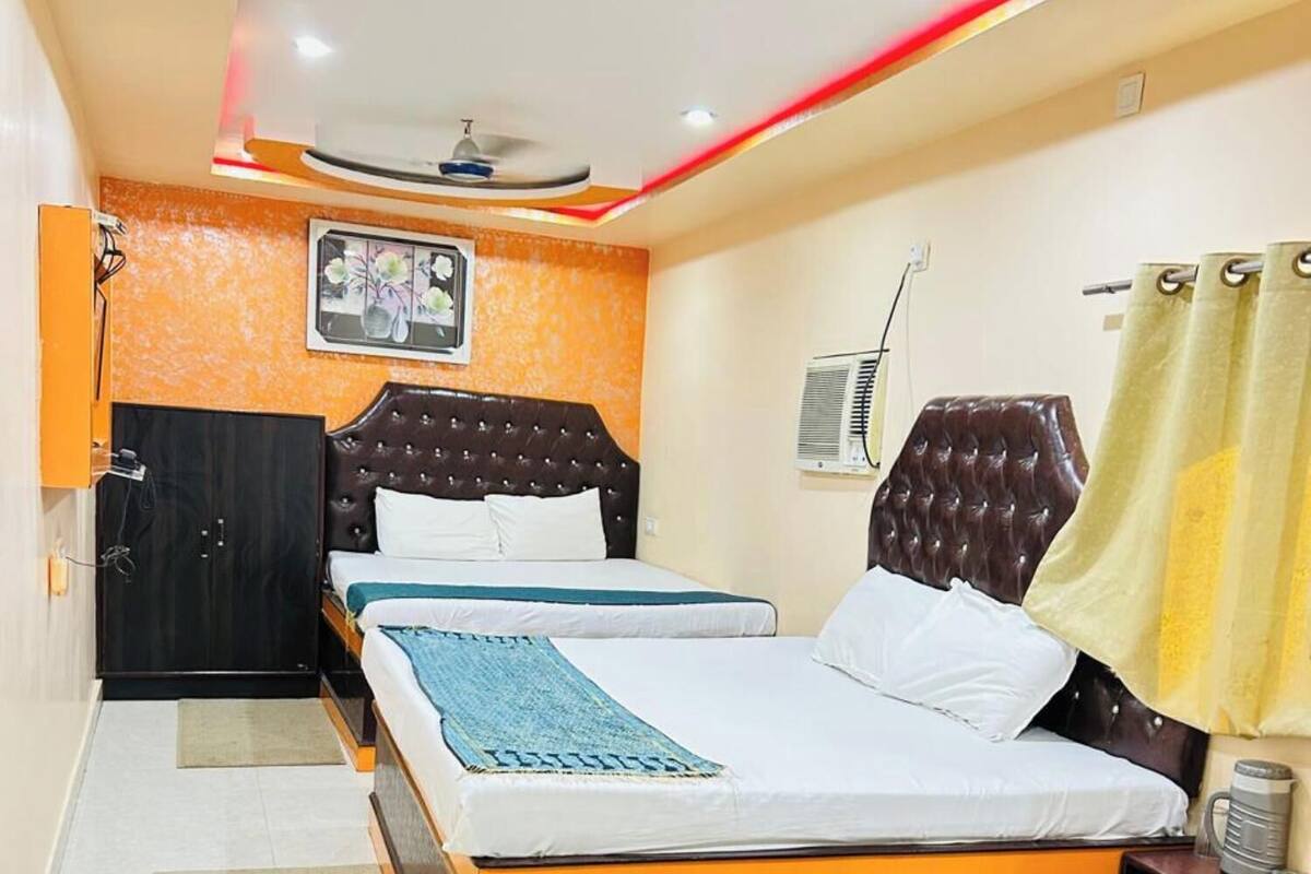 Una habitación de hotel con cama, escritorio, silla, ventilador de techo y aire acondicionado.