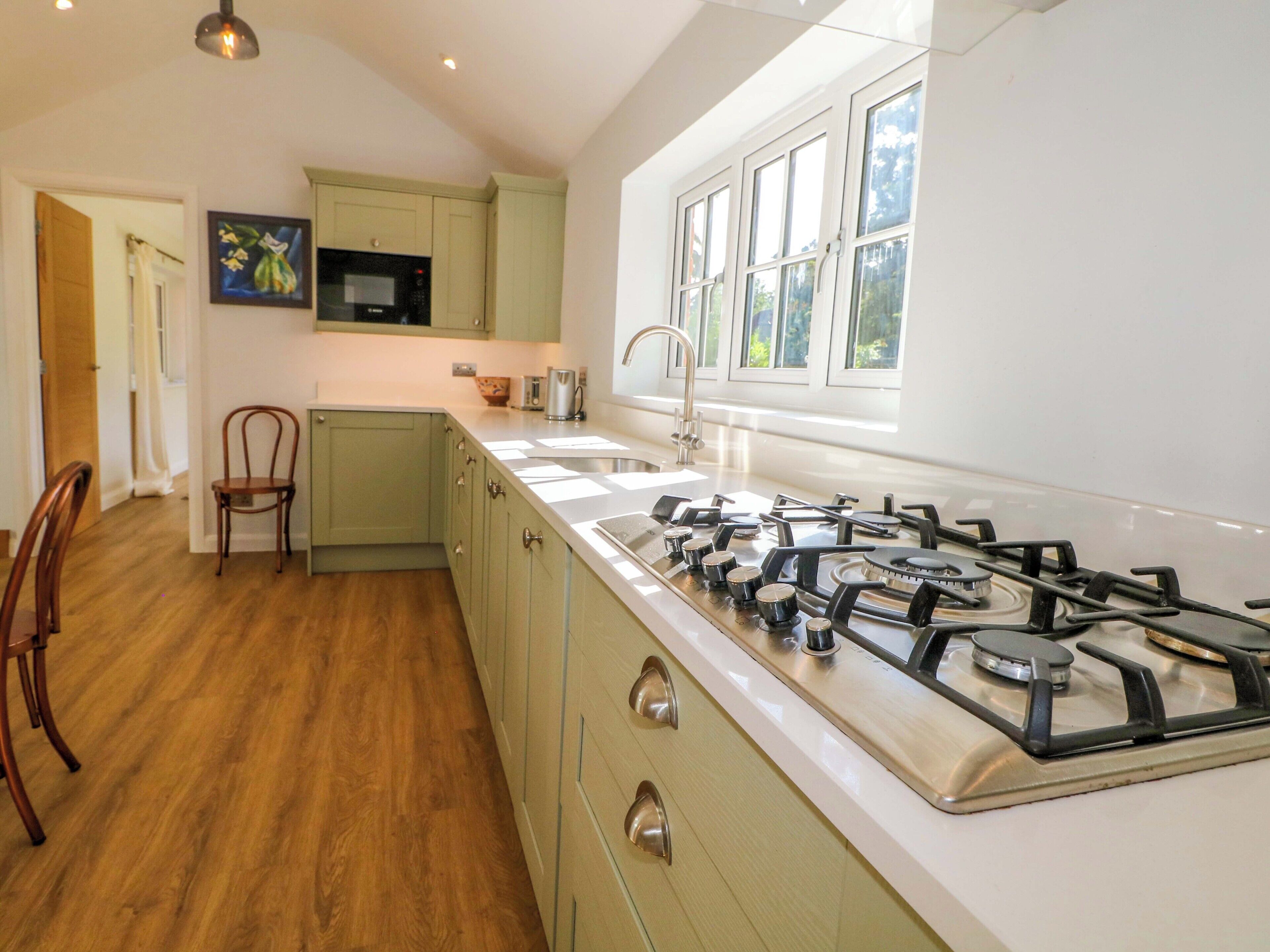 A kitchen with a gas stove, a microwave, and a window with a view of greenery.