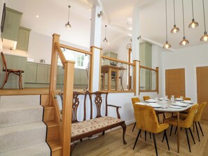 Un área de comedor con una mesa redonda, sillas amarillas y una escalera de madera.