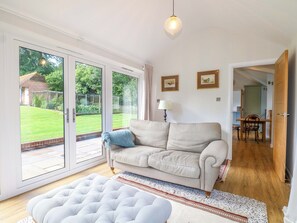 A living room with a sofa, a lamp, a rug, and a view through a glass door to a garden.