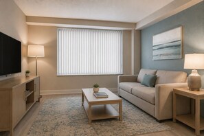 Ein modernes Wohnzimmer mit Flachbildfernseher, einer Couch, einem Couchtisch und einer Lampe.