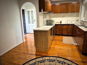 A kitchen with wooden cabinets, a microwave, and a toaster. - Sydney Blue mountain 4 Bedroom Haven (Kingswood)