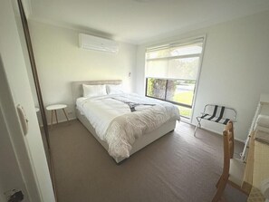 Un dormitorio con una cama, una ventana, una silla y una mesita.