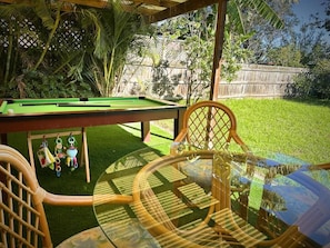 A pool table with a green felt surface, surrounded by a wooden chair and a glass table. - Sydney Blue mountain 4 Bedroom Haven (Kingswood)