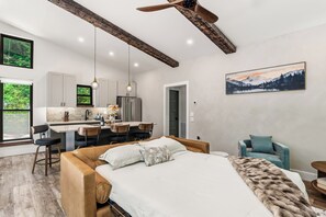 A modern interior with a bed, a dining area, and a kitchen. - The Acosta (Maggie Valley)