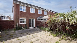 A two-story brick house with a front door, a small front yard, and a garden with flowering plants. - Host & Stay | Urban Nest LIV (Liverpool)
