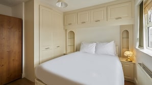 A bedroom with a bed, a nightstand with a lamp, a wooden wardrobe, and a window with a view. - Host & Stay | Urban Nest LIV (Liverpool)