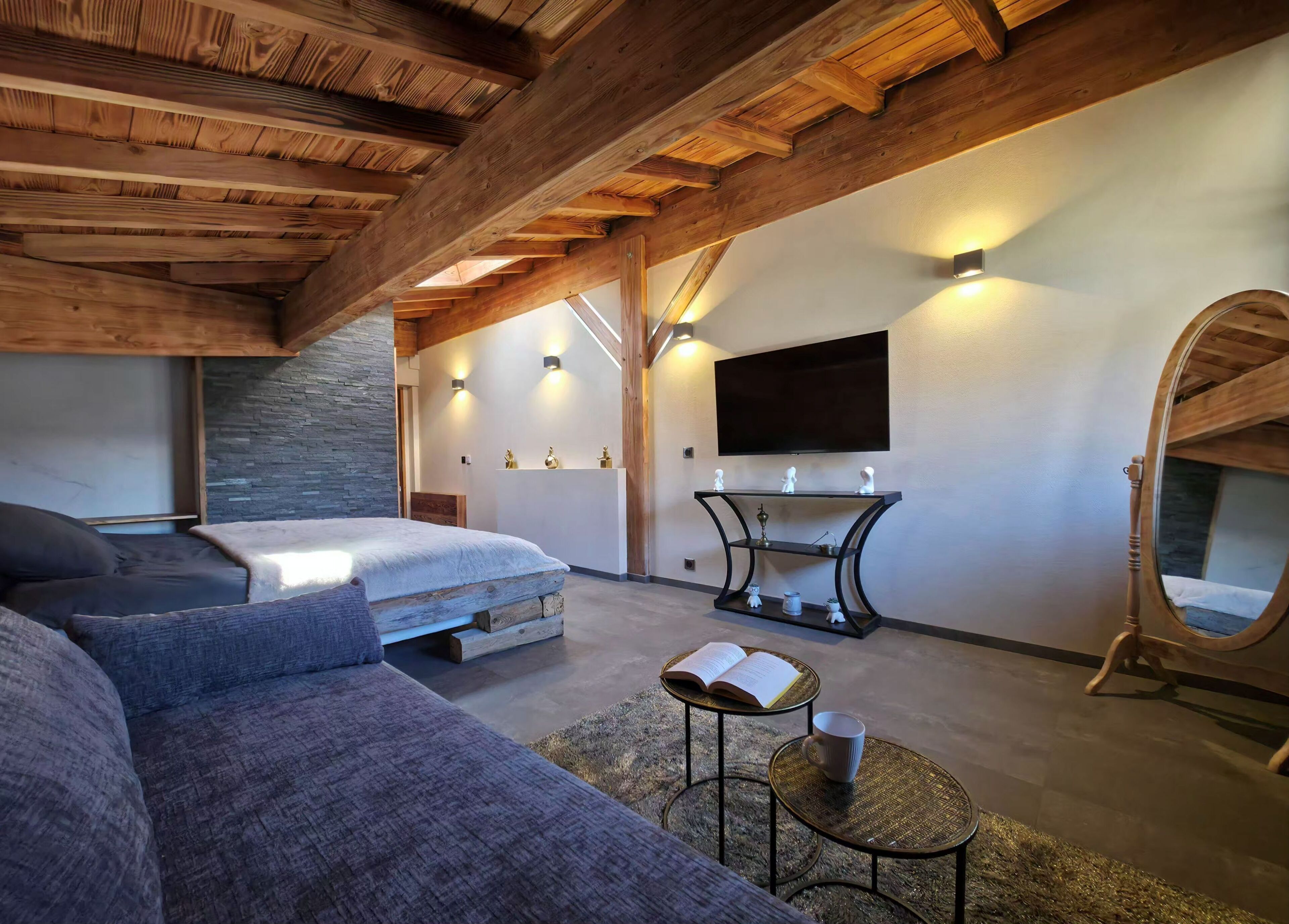 Un intérieur moderne comprenant un lit, un canapé, une télévision, une console et un miroir.