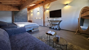 Een modern interieur met een bed, bank, televisie, console tafel en een spiegel.