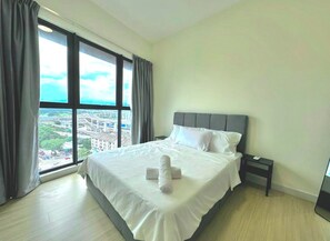 Quarto de hotel com uma cama grande, uma mesa de cabeceira e vista para o horizonte urbano através de uma janela ampla.