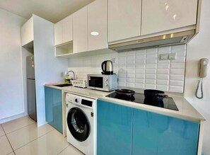 Uma cozinha compacta com máquina de lavar, micro-ondas e fogão pequeno.