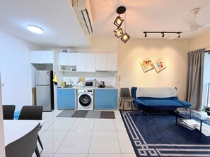 Um espaço compacto com cozinha compacta, sofá, área de refeições e máquina de lavar.