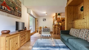 Ein gemütliches Wohnzimmer mit Holzmöbeln, einem Fernseher und einem Essbereich mit Tisch und Stühlen.