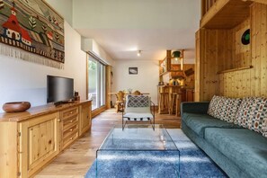 Ein gemütliches Wohnzimmer mit Holzmöbeln, einem Fernseher und einem Essbereich mit Tisch und Stühlen.