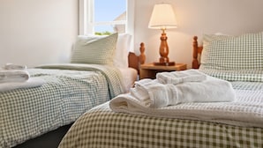 Une chambre d’hôtel avec deux lits, une literie à carreaux, une lampe de chevet et une fenêtre donnant sur un beau paysage.