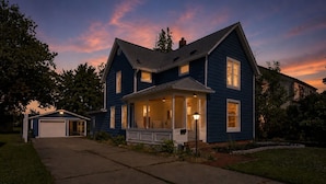 Une maison à deux étages avec un garage, une véranda avec des chaises et une vue sur la rue.
