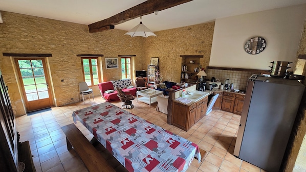 A rustic room with a bed, a sofa, a dining table, and a kitchen area. - Domaine de Rebeyrotte (Pressignac-Vicq)
