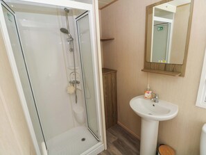 Ein Badezimmer mit einer Duschkabine, einem Waschbecken und einem Spiegel.