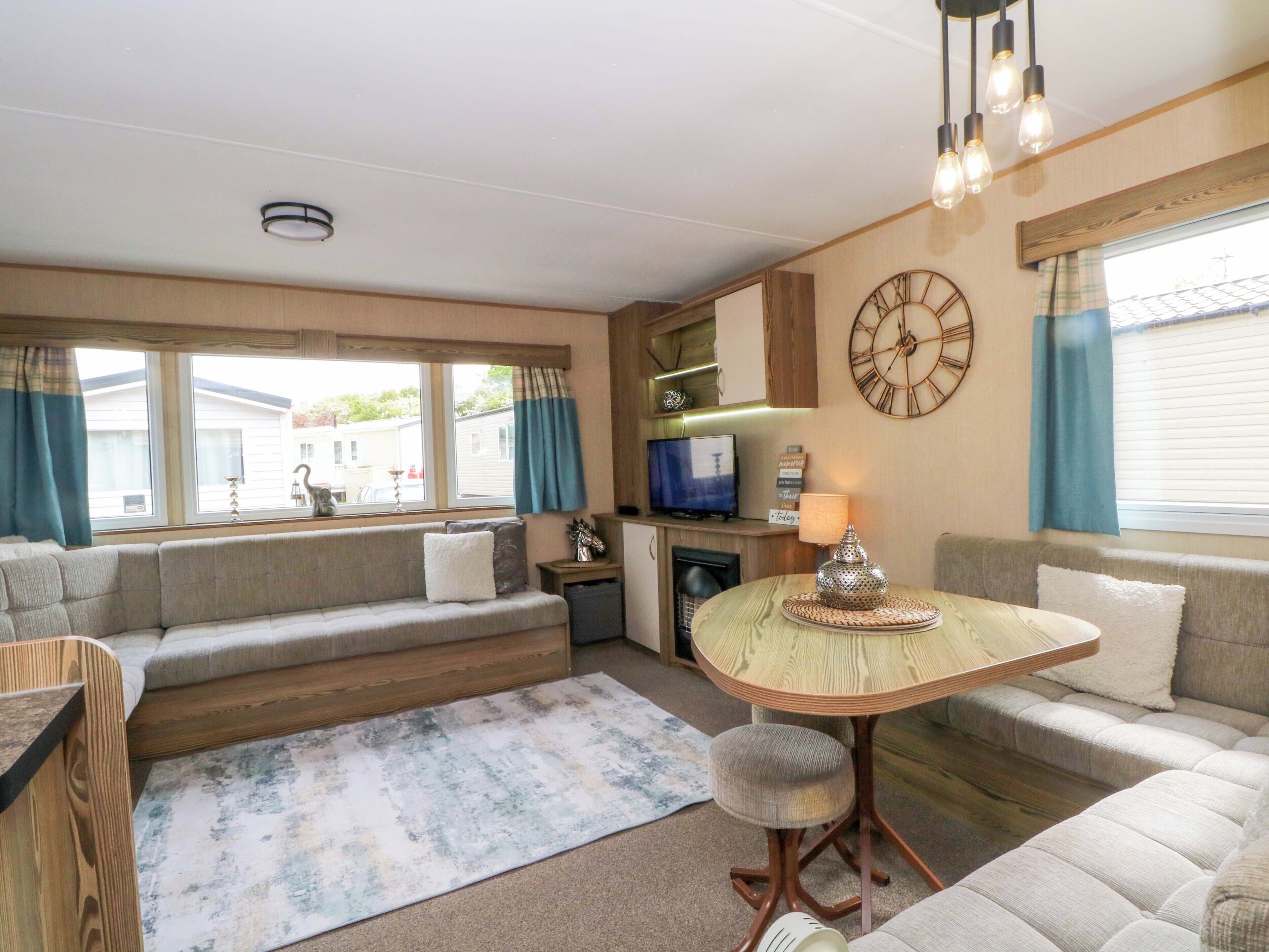 A cozy living area with a sofa, a small round table, a television, and a clock on the wall.