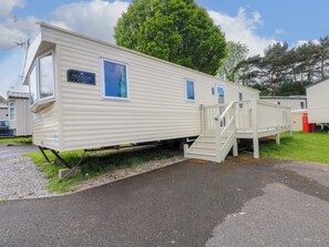 Ein Wohnmobil mit separatem Schlafbereich, einer kleinen Veranda und einer Treppe zum Eingang.