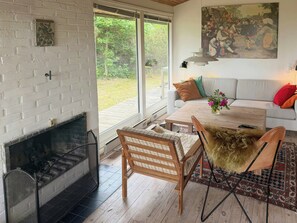 Ein Zimmer mit Kamin, einer Couch, einem Couchtisch und einem Gemälde an der Wand.