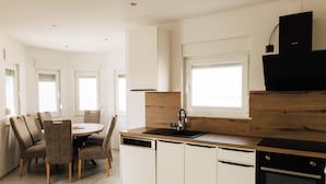 A modern kitchen with white cabinetry, a wooden countertop, a dishwasher, and an oven. - Golden Hour – Exclusive Holiday Home with Sea Views in Croatia (Slivnica)
