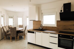 Eine moderne Küche mit weißen Schränken, einer Holzarbeitsplatte, einem Geschirrspüler und einem Backofen.