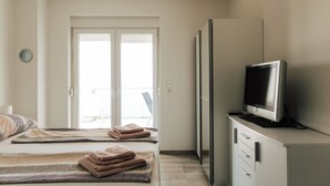 A hotel room with a bed, a television on a cabinet, and a door leading to an outdoor area. - Golden Hour – Exclusive Holiday Home with Sea Views in Croatia (Slivnica)