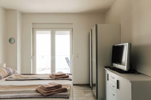 Ein Hotelzimmer mit einem Bett, einem Fernseher auf einem Schrank und einer Tür zu einem Außenbereich.