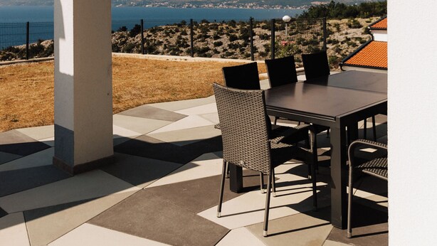 A patio with a table and chairs, a view of mountains, and a body of water. - Golden Hour – Exclusive Holiday Home with Sea Views in Croatia (Slivnica)