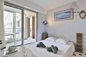 Ein Hotelzimmer mit Bett, Tisch mit Tasse und Untertasse, Stuhl, einer Wandablage und einem gerahmten Bild.