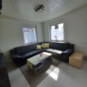 En stue med en sort lædersofa, et sofabord og en radiator.